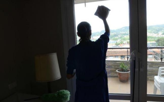 Empleada del hogar limpiando unos cristales.