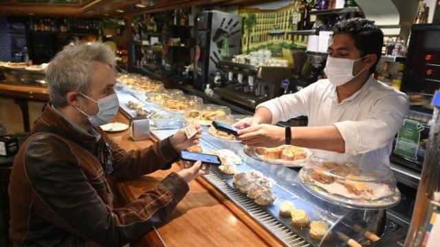 Un cliente muestra su pasaporte covid al responsable de un local hostelero en Bilbao.