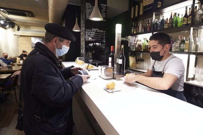 Un cliente atendido por el camarero de un bar pamplonés este martes, primer día sin restricciones.