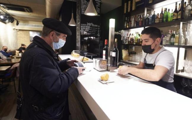 Un cliente atendido por el camarero de un bar pamplonés este martes, primer día sin restricciones.