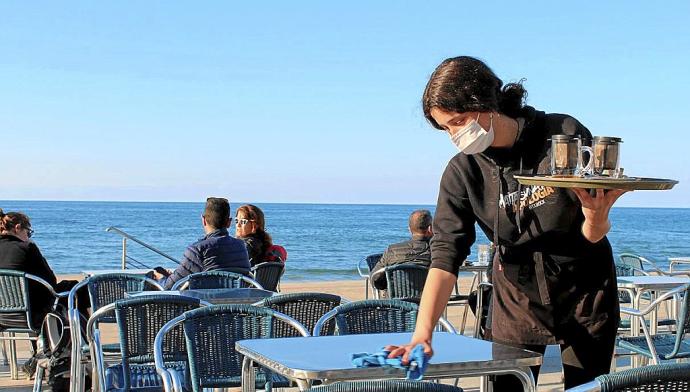 Una camarera del bar Xarabi de Zarautz limpia la mesa después de recogerla.