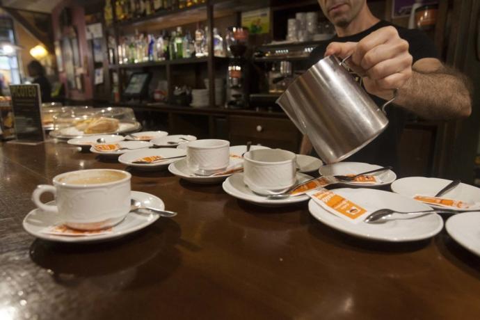 Un camarero prepara unos cafés en la barra del bar.