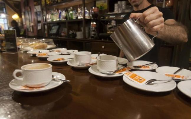 Un camarero prepara unos cafés en la barra del bar.