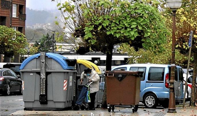 Una mujer deposita residuos en unos contenedores de reciclaje.