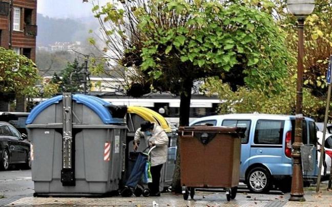 Una mujer deposita residuos en unos contenedores de reciclaje.