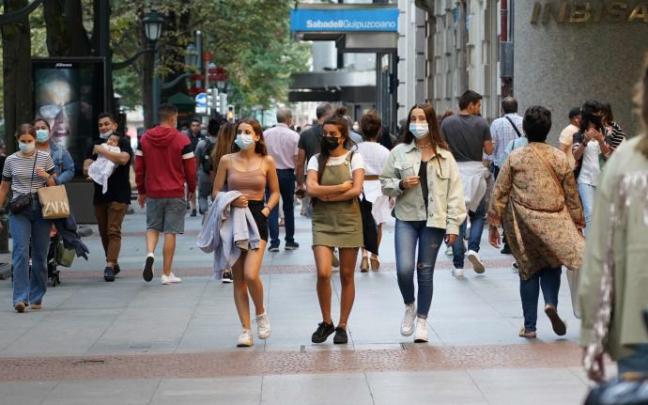 Varias personas pasean protegidas con mascarillas por la pandemia de coronavirus