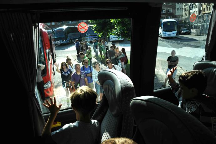 Niños se despiden de sus padres en el autobús.