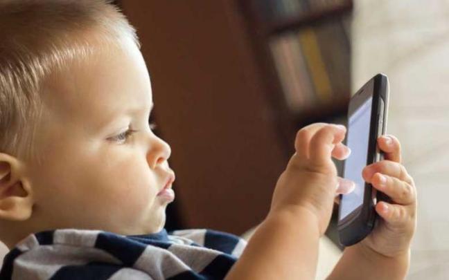 Un niño jugando con un móvil Un niño jugando con un móvil