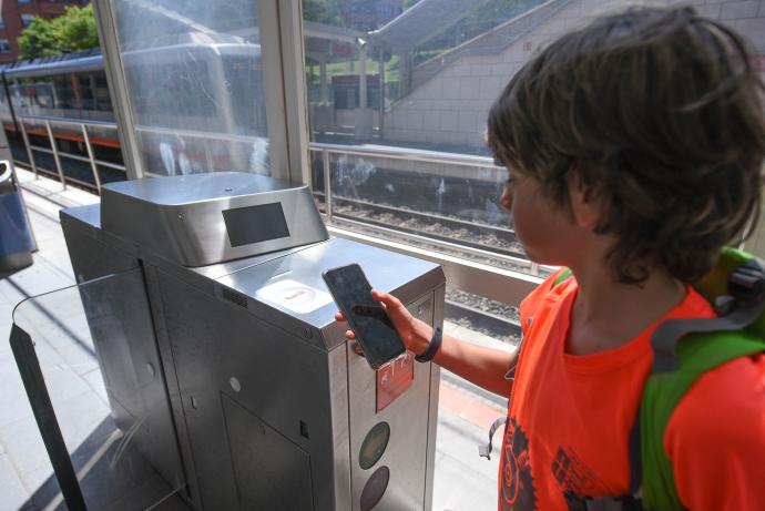 Un usuario consulta su teléfono móvil junto a una de las canceladoras de la red de Metro Bilbao, que permitirán el abono de viajes con estos terminales.