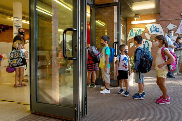 Niños con mascarilla hacen cola para entrar de forma escalonada en un colegio de Barcelona.