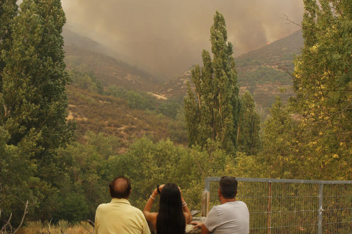 Tres vecinos observan el incendio de Navalacruz (Ávila), que ha arrasado casi 22.000 hectáreas.