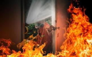 Un bombero entra en una vivienda en llamas. Un bombero entra en una vivienda en llamas.