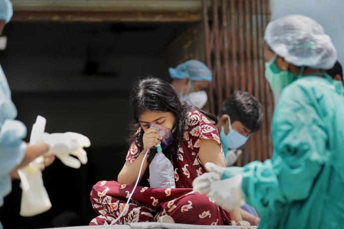 Una niña india recibe oxígeno a la puerta de un hospital
