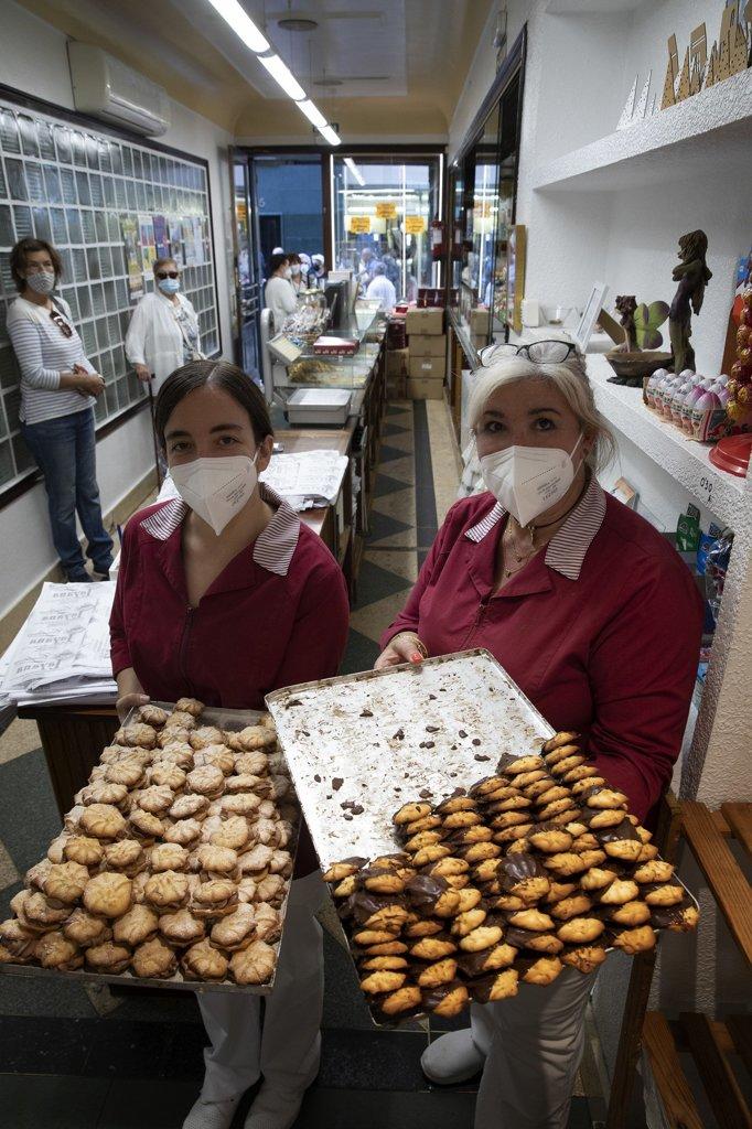 Juani Ruiz y Leire Aranguren, trabajadoras en la confitería Layana, posan con dos bandejas de pastas rellenas y simples.