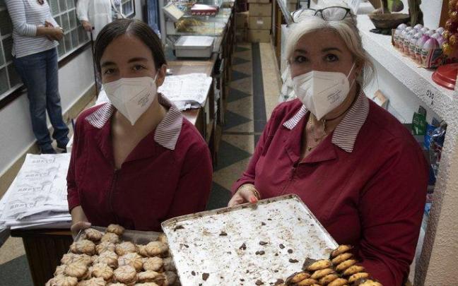 Juani Ruiz y Leire Aranguren, trabajadoras en la confitería Layana, posan con dos bandejas de pastas rellenas y simples.