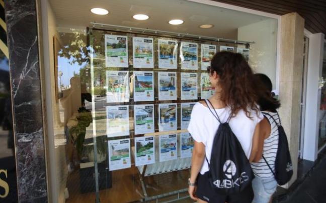 Dos personas miran anuncios en una inmobiliaria.