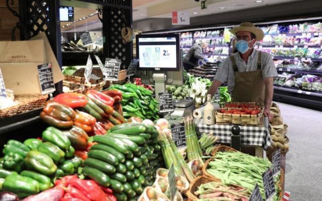 Un empleado con mascarilla y guantes trabajando en un supermercado.