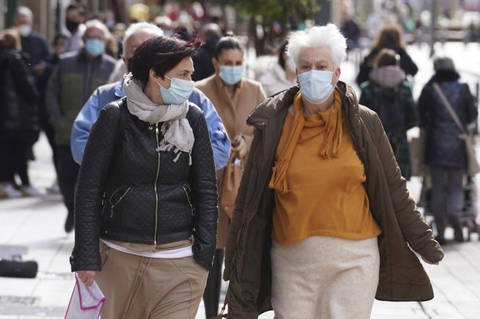 Varias personas andando por la calle con mascarilla para evitar contagios de coronavirus.