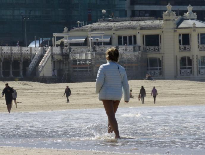 Una mujer se refresca los pies en la playa de La Concha de Donostia