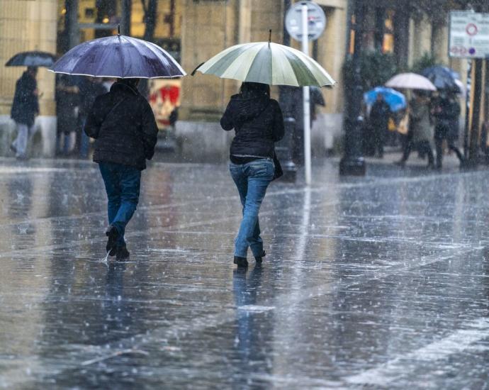 Dos personas se protegen de la lluvia con paraguas en Donostia