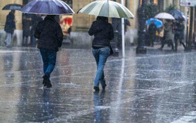Dos personas se protegen de la lluvia con paraguas en Donostia