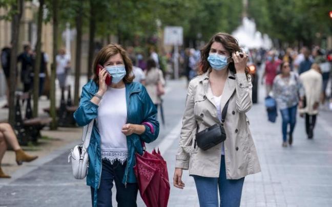 Dos mujeres pasean por la calle con mascarilla.