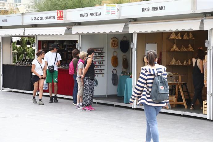 Varias personas pasean junto a los puestos de artesanía en Donostia