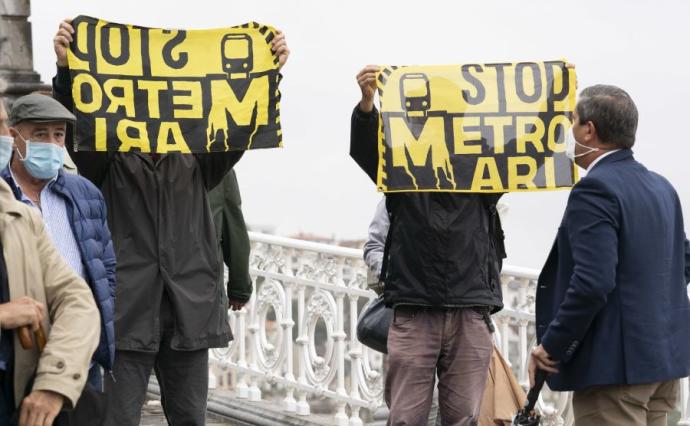 Dos personas sujetan carteles en contra de las obras del Topo.