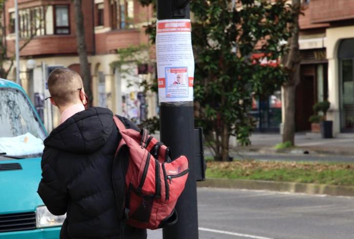 Un joven revisa un cartel con los datos del desaparecido.