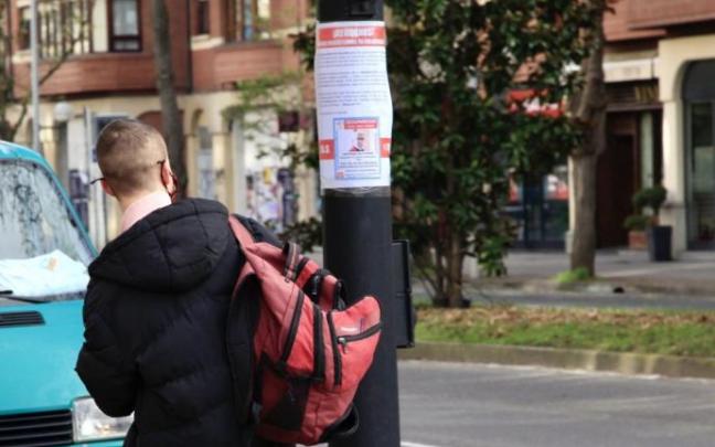 Un joven revisa un cartel con los datos del desaparecido. Un joven revisa un cartel con los datos del desaparecido.
