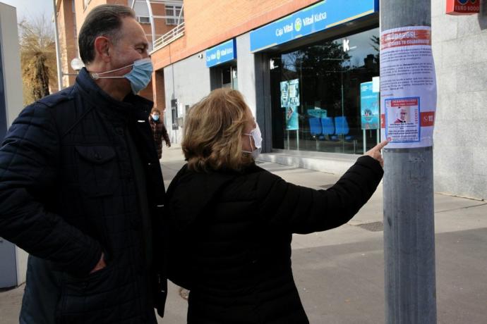 Dos personas observan un cartel con los datos de búsqueda de Jesús Bengoa.