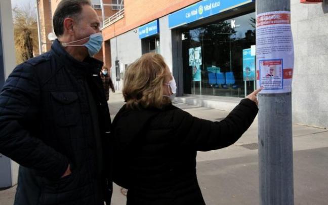 Dos personas observan un cartel con los datos de búsqueda de Jesús Bengoa.