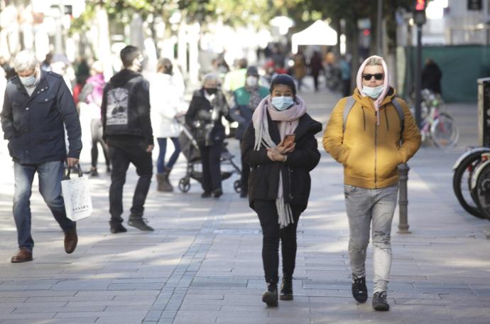 Personas andando por la calle con mascarilla.