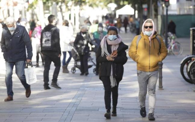 Personas andando por la calle con mascarilla.