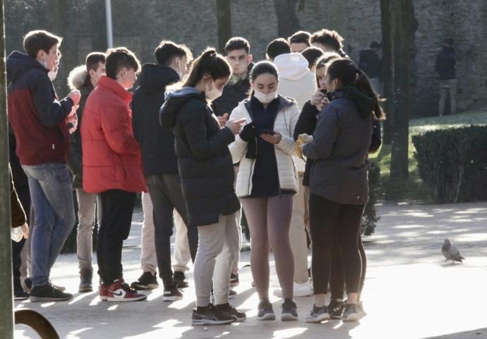 Un grupo de jçovenes ajenos a esta información contemplan sus móviles.