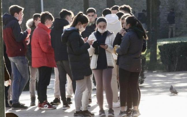 Un grupo de jçovenes ajenos a esta información contemplan sus móviles.