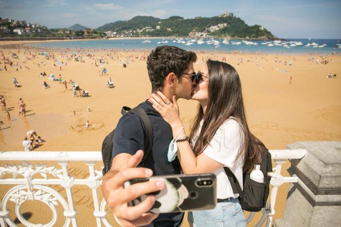 Una pareja se hace un selfie con la playa de La Concha de fondo