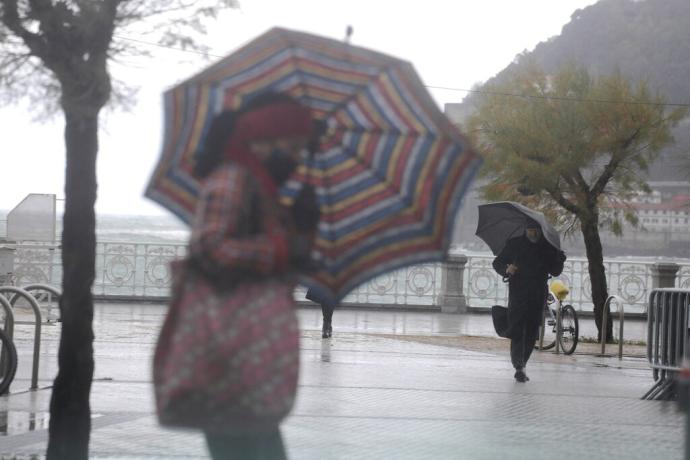 Dos personas se protegen con paraguas en Donostia