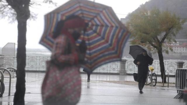 Dos personas se protegen con paraguas en Donostia