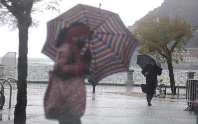 Dos personas se protegen con paraguas en Donostia Dos personas se protegen con paraguas en Donostia