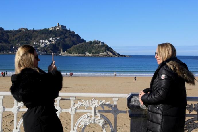 Dos turistas se fotografían ante la bahía de La Concha