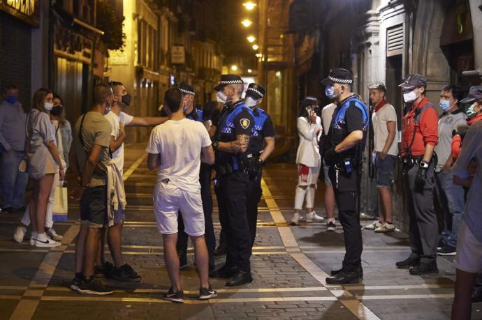 Agentes de Policía Municipal y Foral conversan con unos jóvenes.