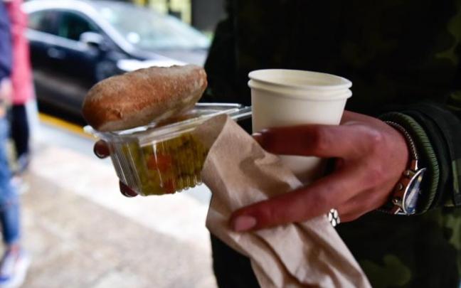 Una persona recoge una ración de cena en Donostia.