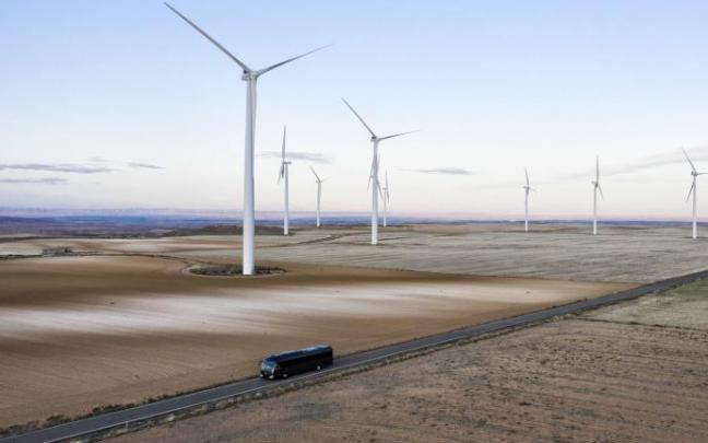 Un modelo eléctrico de Irizar atraviesa un parque eólico.