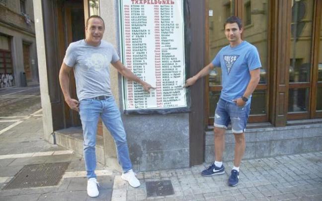 Irujo (i) y Retegi Bi, señalando al año 2014 en el cartel de campeones del Manomanista del bar Kantxa de Pamplona. Irujo (i) y Retegi Bi, señalando al año 2014 en el cartel de campeones del Manomanista del bar Kantxa de Pamplona.
