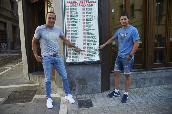 Irujo (i) y Retegi Bi, señalando al año 2014 en el cartel de campeones del Manomanista del bar Kantxa de Pamplona.