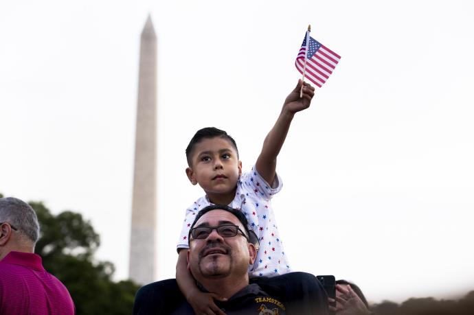 Un hombre sigue junto a su hijo el discurso de Biden en el Día de la Independencia