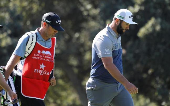 Jon Rahm y su caddie Adam Hayes caminan cabizbajos por el campo de Valderrama ayer jueves.