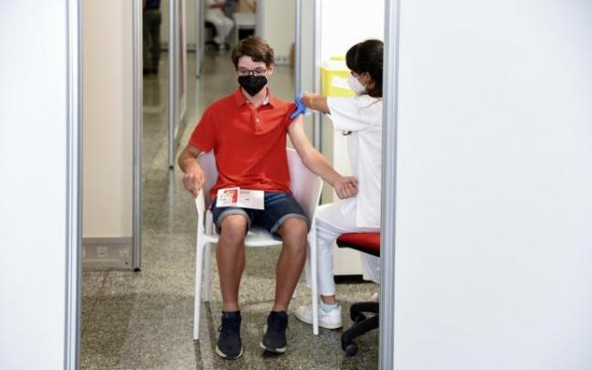 Una sanitaria vacuna a un adolescente con la primera dosis de la vacuna.
