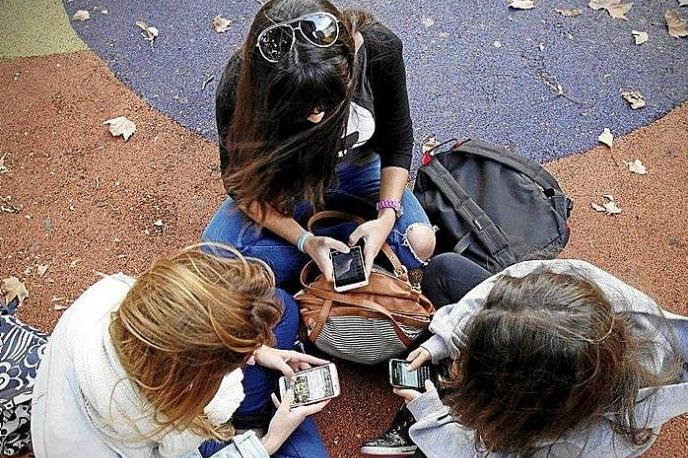 Tres jóvenes revisan sus móviles.